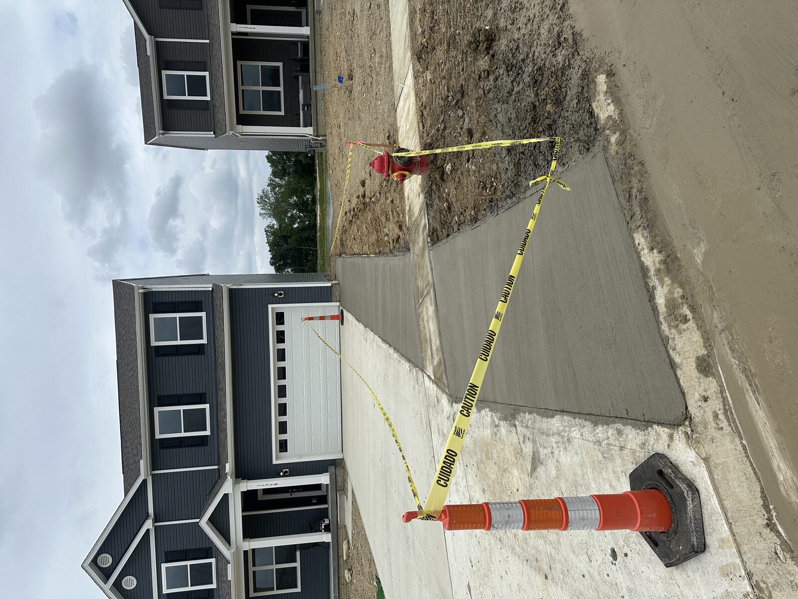 Freshly poured concrete sidewalk section marked with caution tape