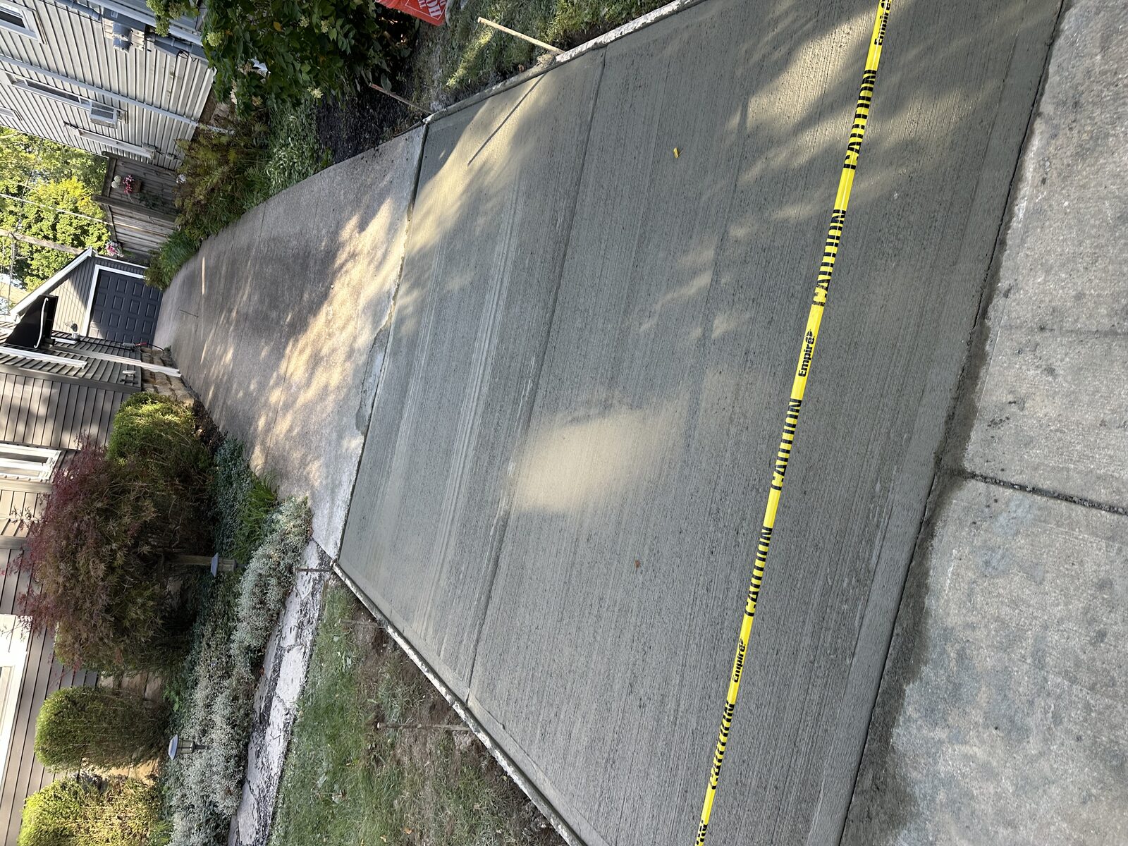 New broom-finished concrete walkway with caution tape in front of a home
